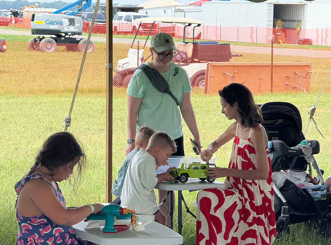 Families work together at activity stations, building and exploring hands-on projects inside the Hands On Hangar tent at Thunder Over Michigan.